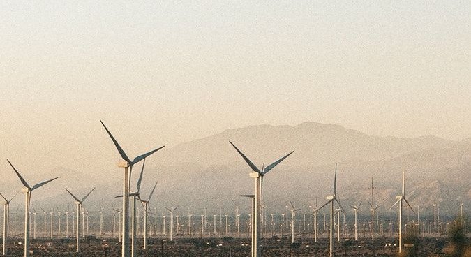 A wind farm stretching across a hazy desert valley at sunrise