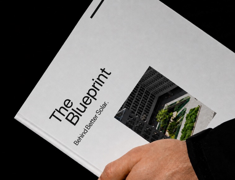 Hands holding a printed report titled The Blueprint, Behind Better Solar